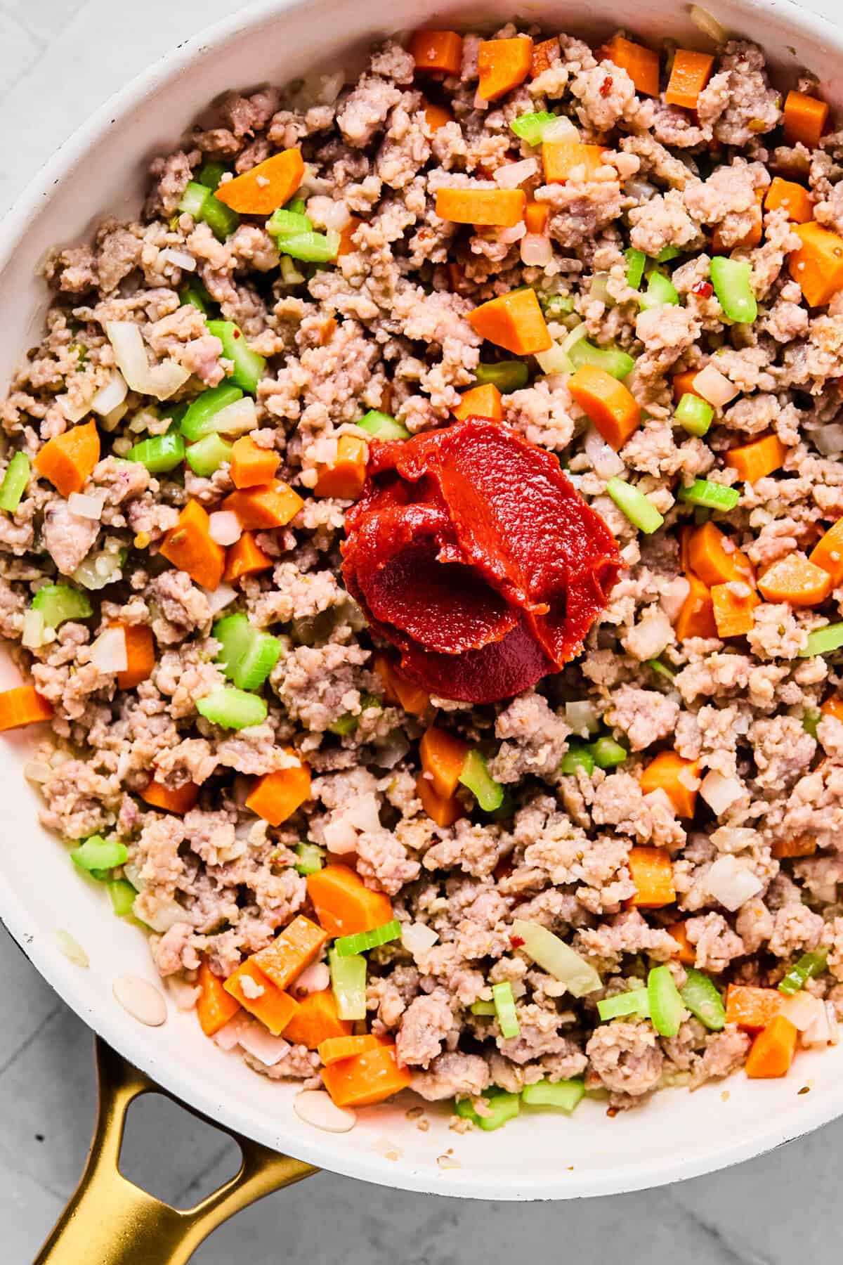 adding the veggies and tomato paste to the skillet 