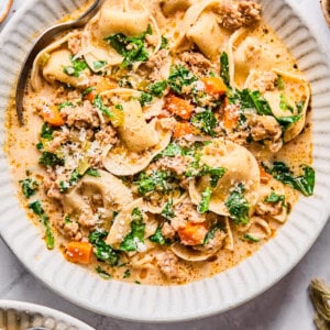 Sausage and tortellini soup in a white bowl