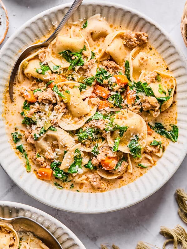 Sausage and tortellini soup in a white bowl