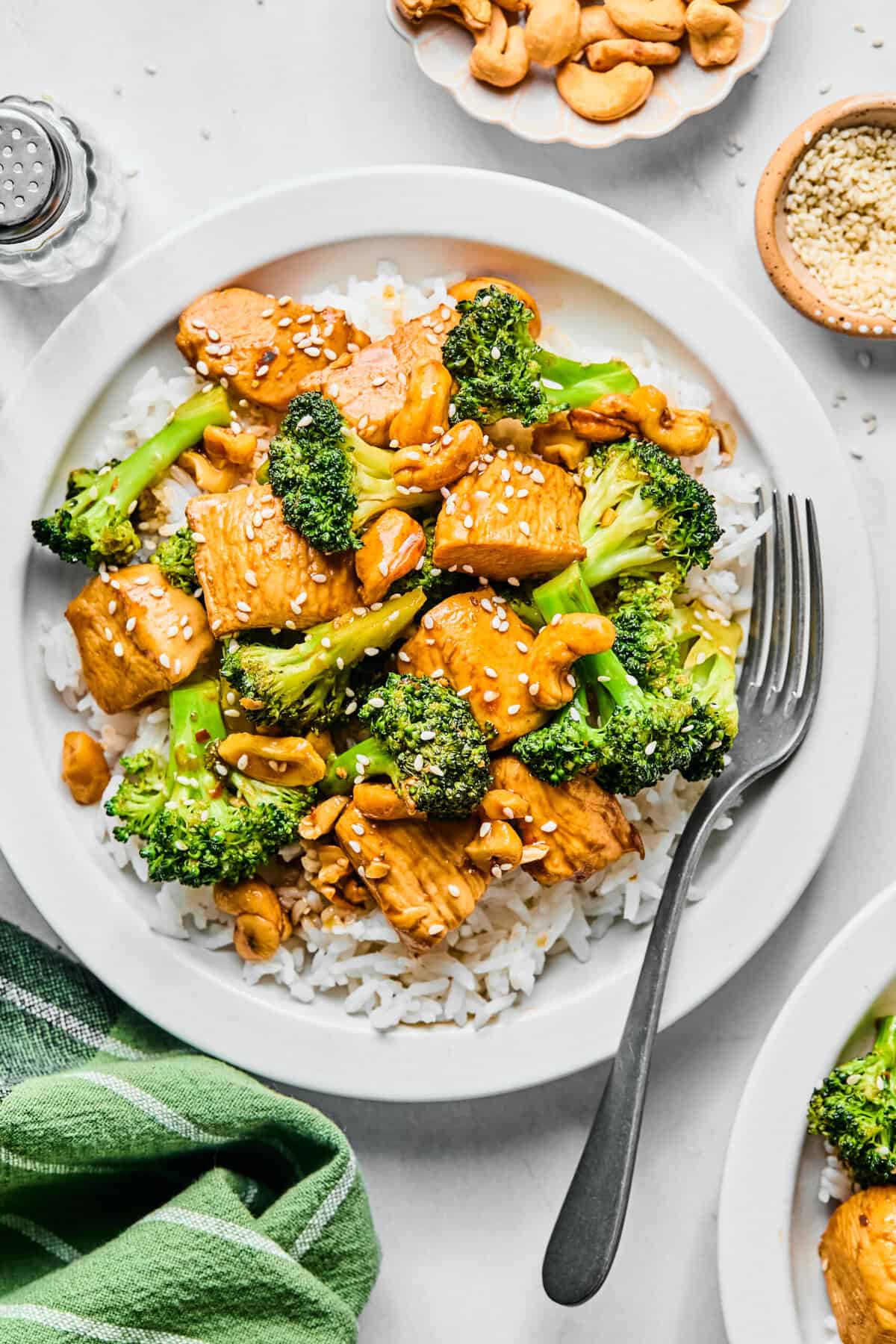 chicken broccoli stir fry over white rice on a white plate