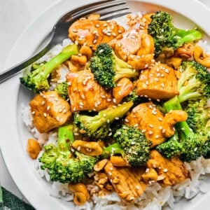 chicken and broccoli stir fry over white rice on a plate with a fork