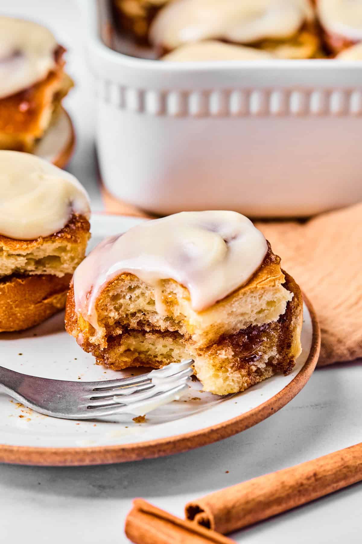 a cinnamon roll on a plate with a bite taken out