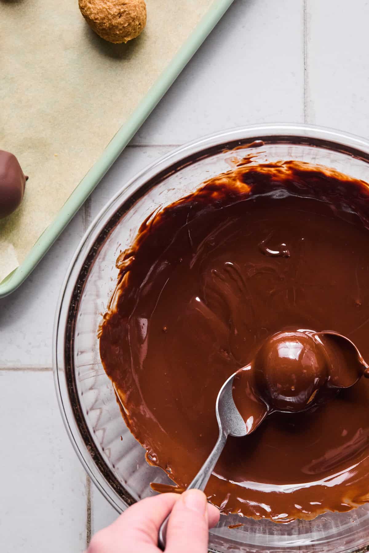 2 spoons dipping a peanut butter ball in chocolate