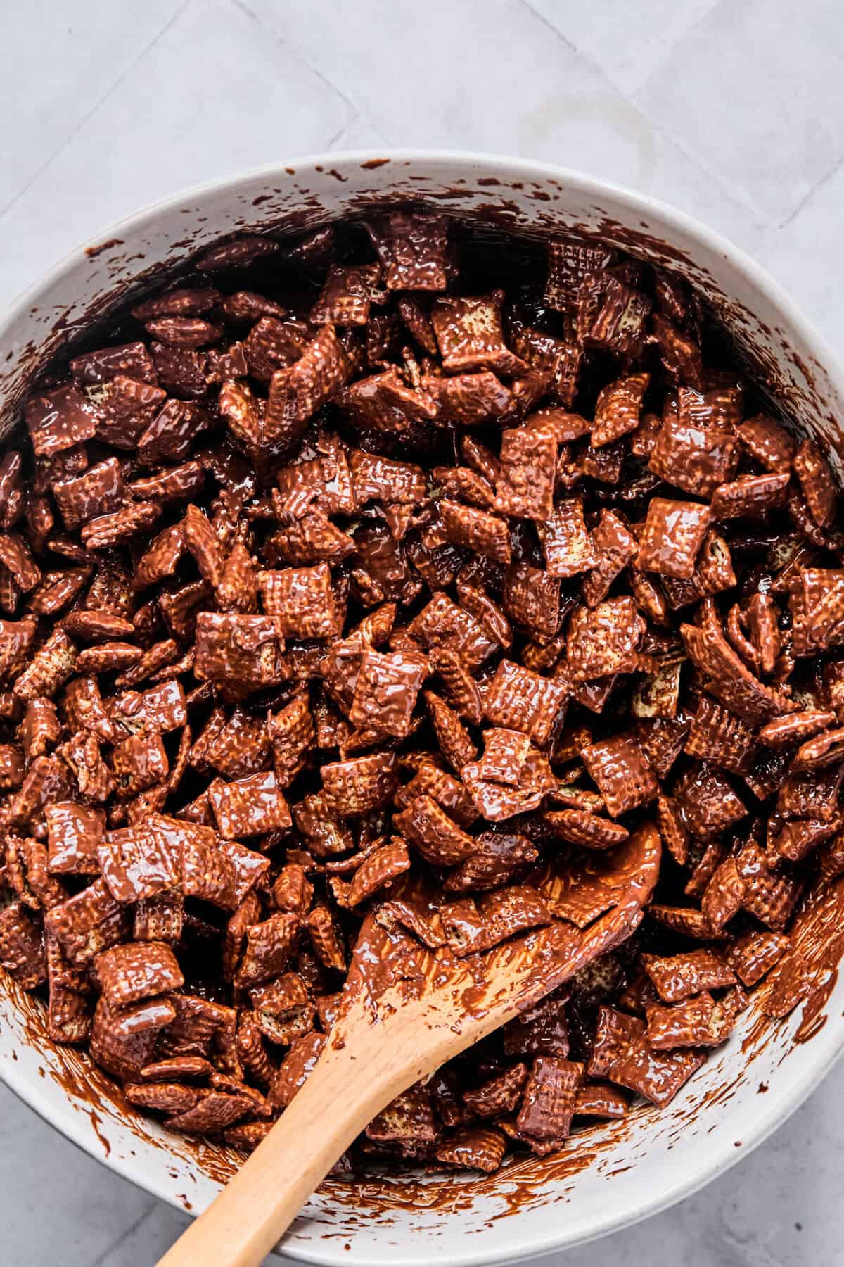 Chex cereal gently tossed in a bowl until evenly coated with the melted chocolate peanut butter mixture.