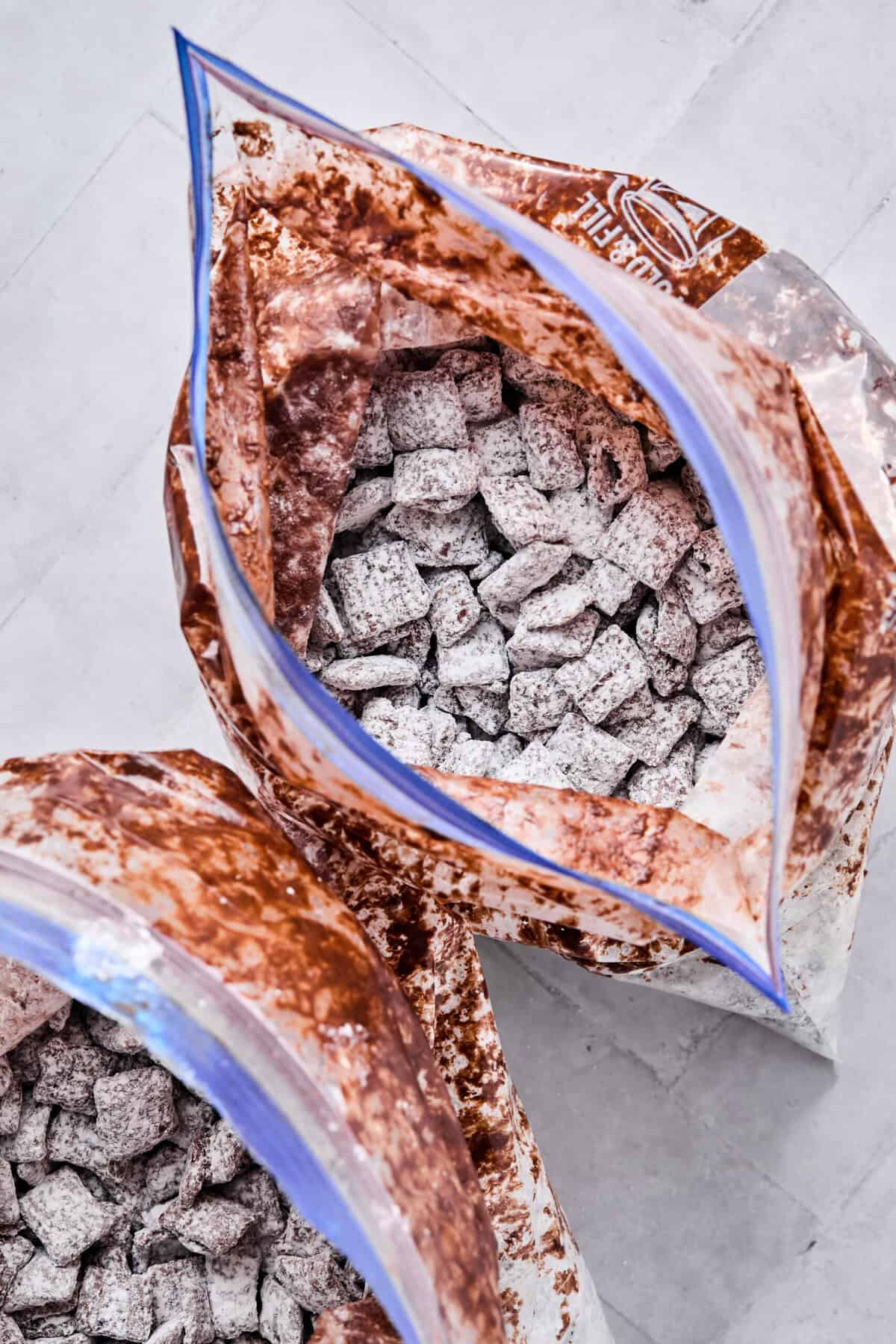 Chocolate-coated cereal divided between two gallon-sized zip-top bags and shaken with powdered sugar until fully coated.