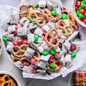 gluten free reindeer chow / Christmas Muddy Buddies in a holiday tin with tissue paper surrounded by mix-ins