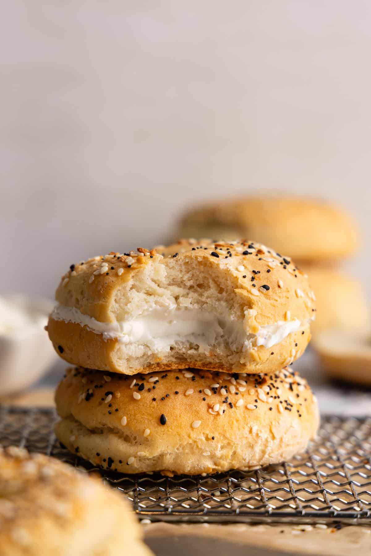 Two cottage cheese bagels stacked on top of each other; the top one is filled with cream cheese.