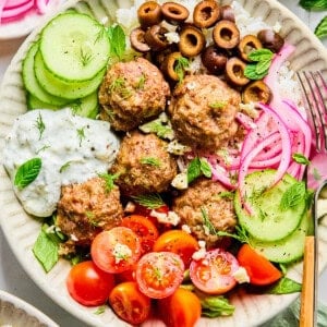 Greek lamb meatballs in a bowl with veggies and lemon dill feta sauce