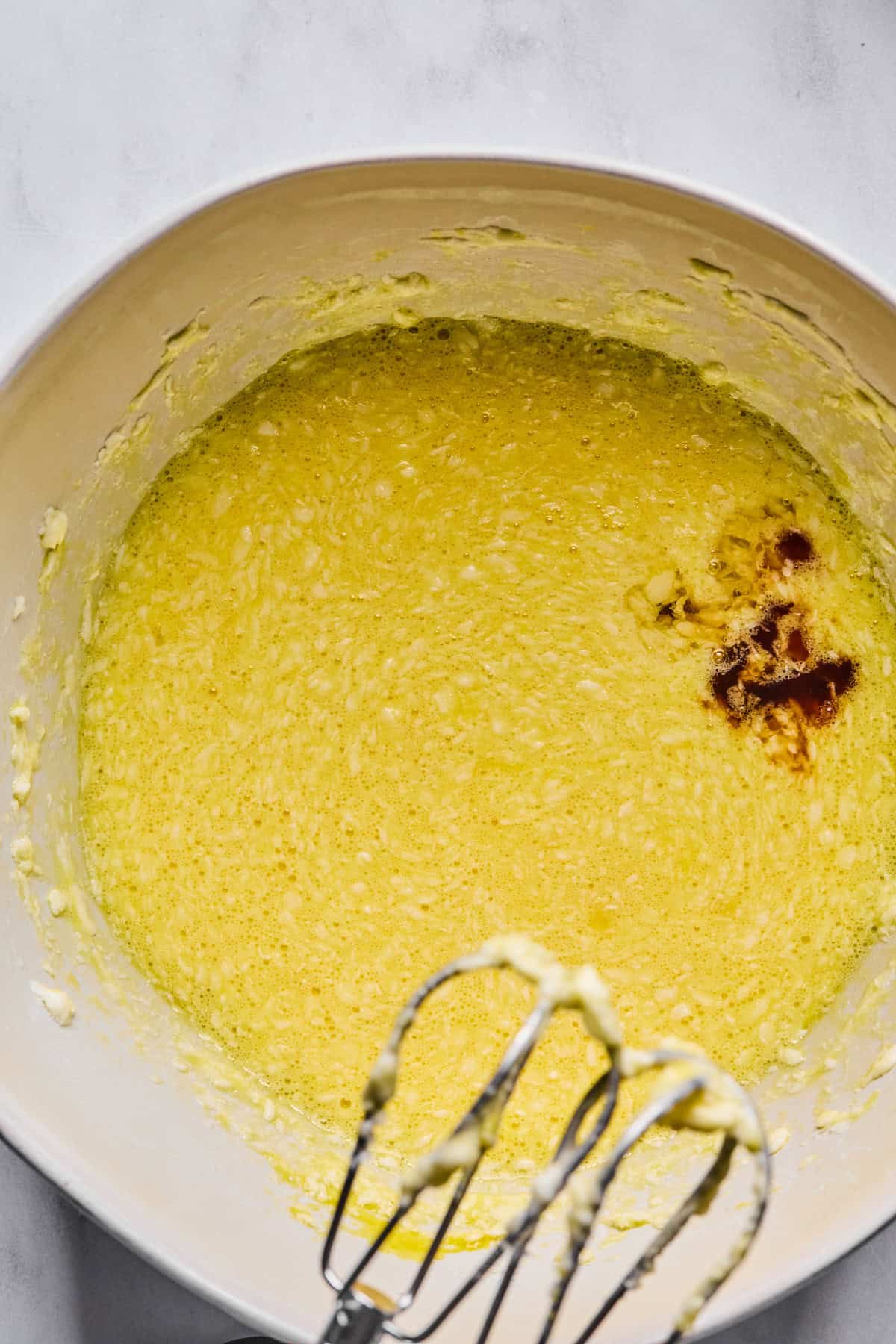 Eggs mixed into the batter in a large mixing bowl, with vanilla and almond extracts added and blended until smooth.