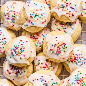 Italian wedding cookies with sprinkles piled on a cooling rack