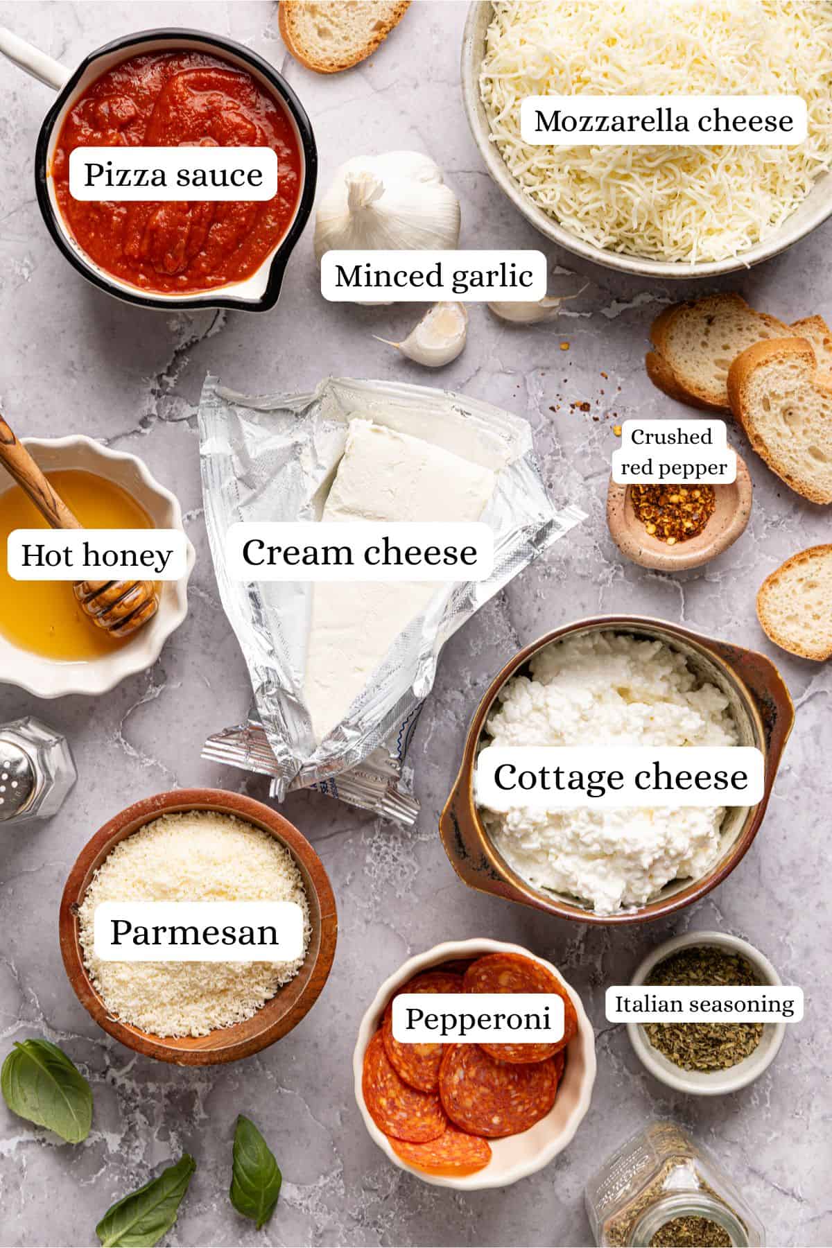 High protein pizza dip ingredients labeled and laid out in nesting bowls on a light gray countertop.