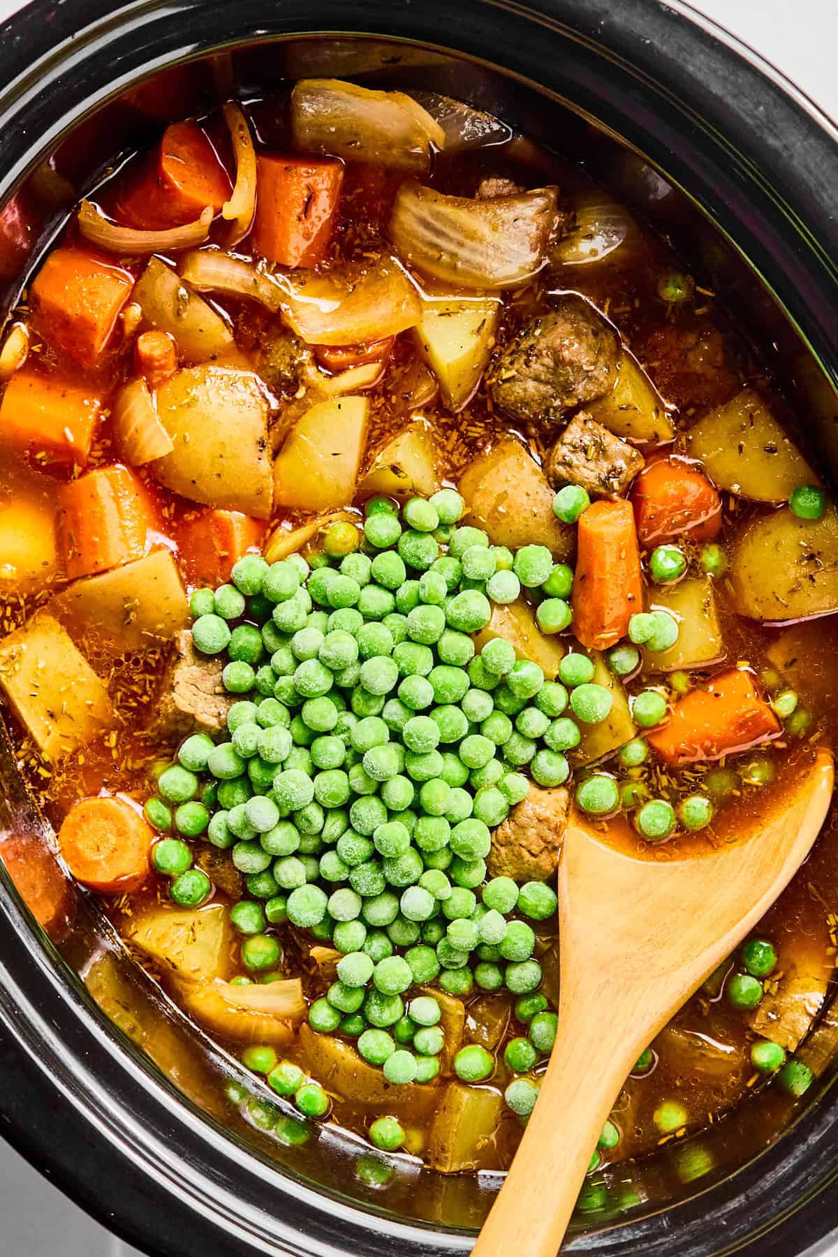 Peas, stew meat, carrots, potatoes, Worcestershire sauce, hot sauce, rosemary, thyme, salt, and pepper in a slow cooker.