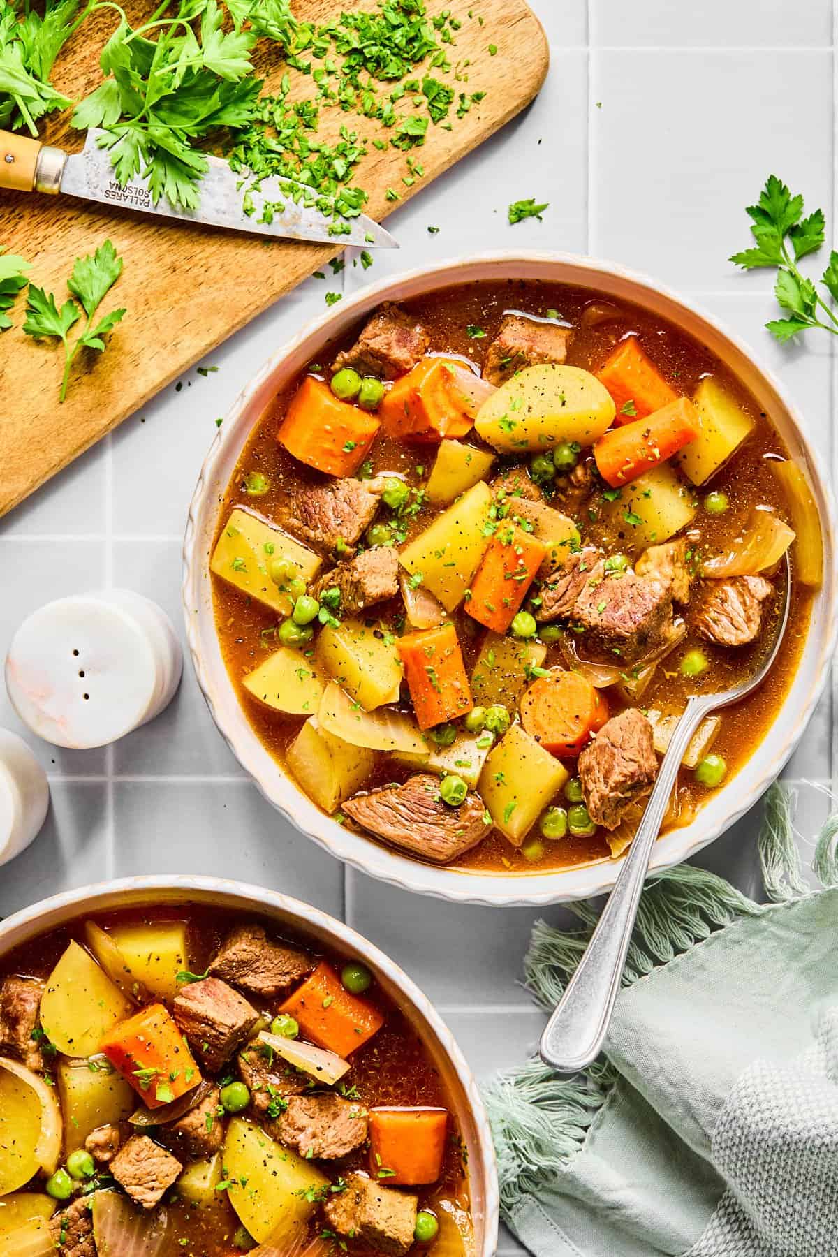 Two bowls of slow cooker beef stew on a light gray colored countertop.