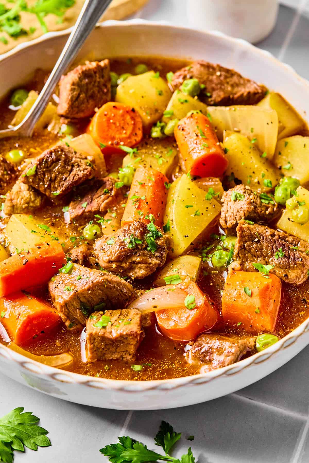 A bowl of slow cooker beef stew with a spoon in it.