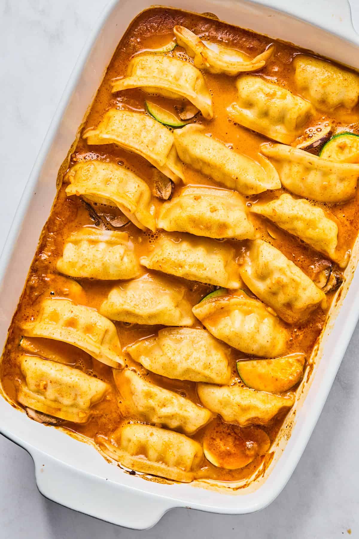 Potstickers baked in a sauce in a casserole dish