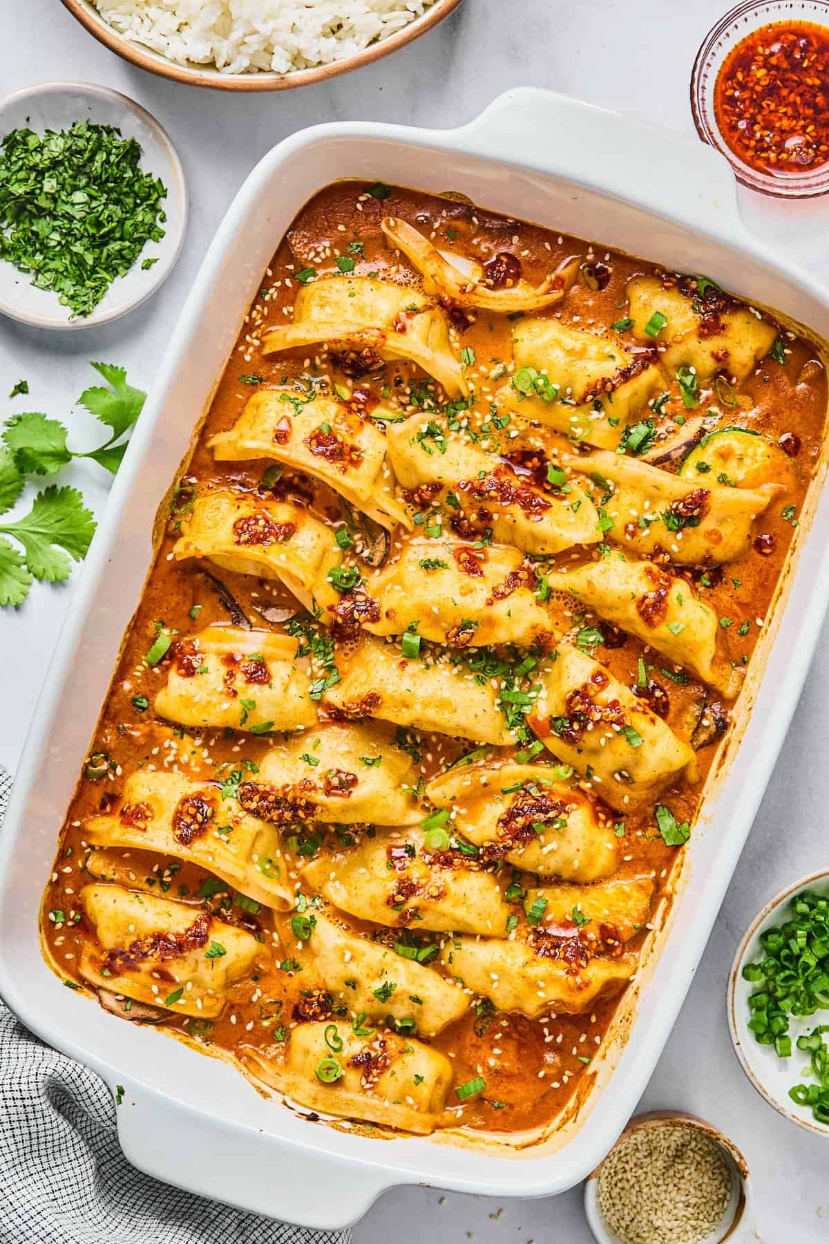 the viral dumpling bake in a casserole dish topped with cilantro and green onions and chili crunch