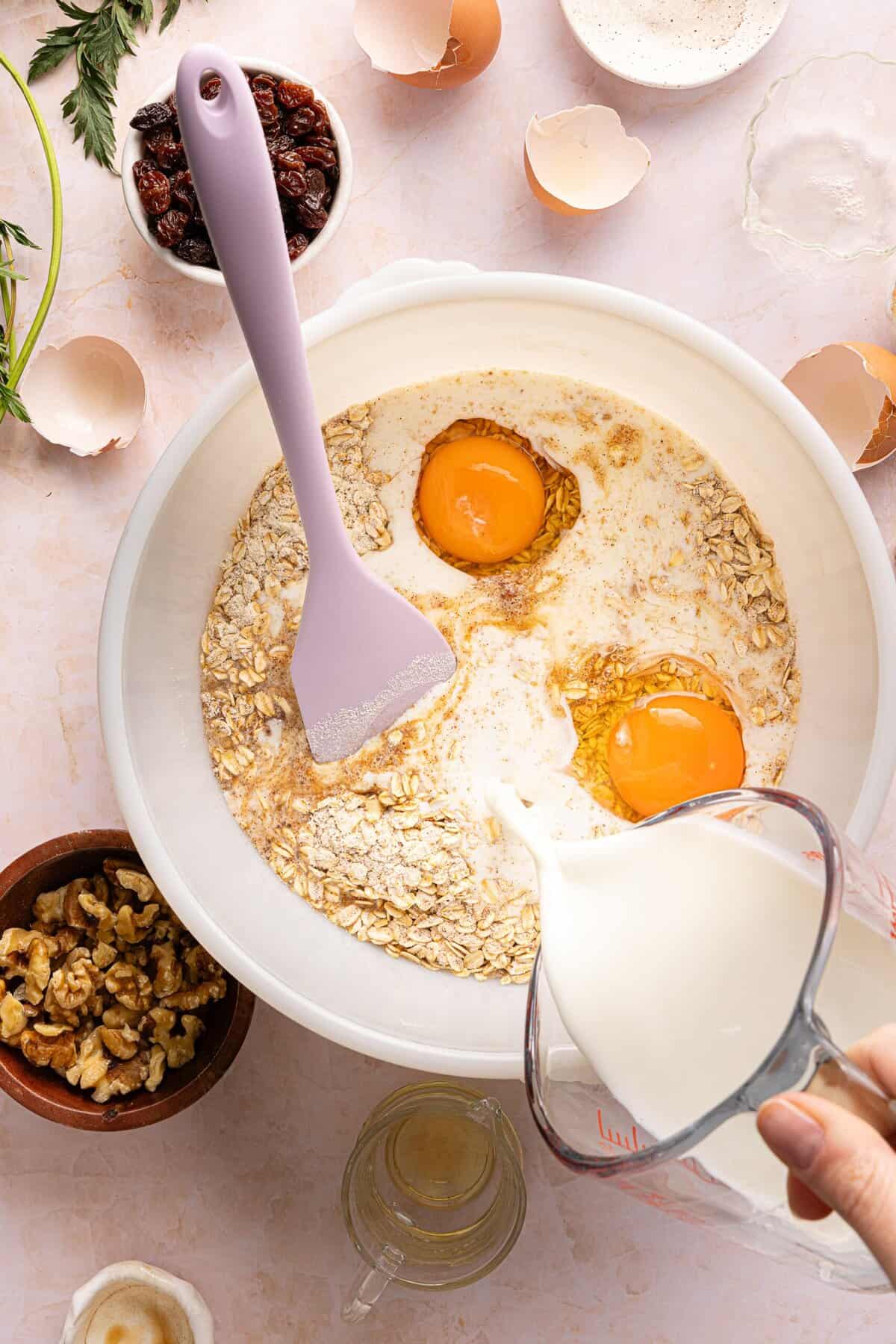 Eggs, egg whites, maple syrup, milk, and vanilla added to the oat mixture for carrot cake baked oats batter.