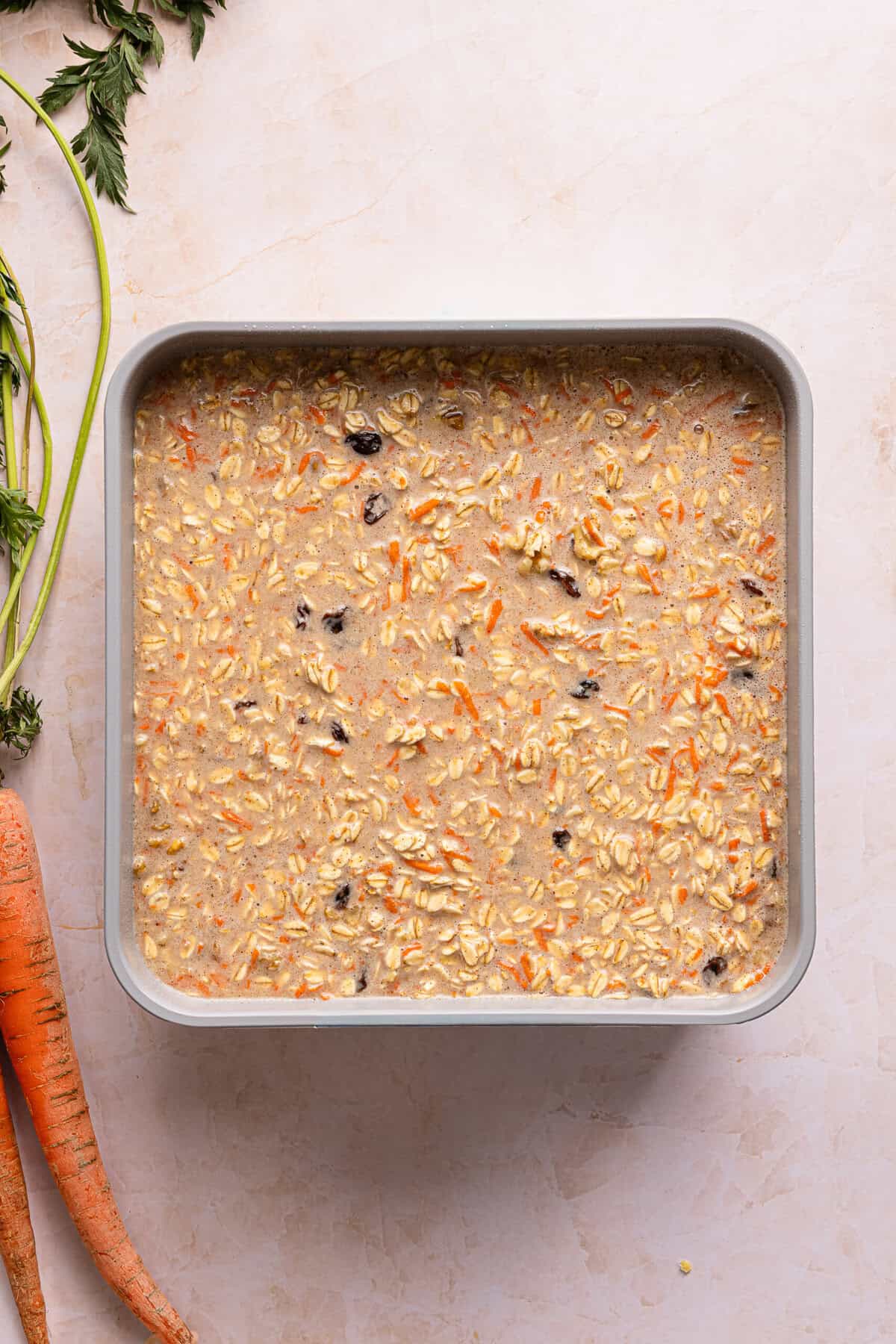 Carrot cake baked oats batter poured into a greased 9x9 metal baking dish before baking.