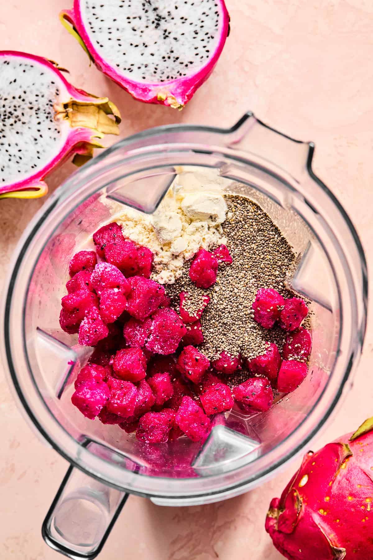 Frozen dragon fruit, banana slices, vanilla protein powder, chia seeds, and coconut water in a high-speed blender.