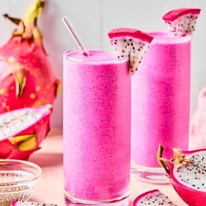 dragon fruit smoothies in 2 cups surrounded by dragonfruit pieces