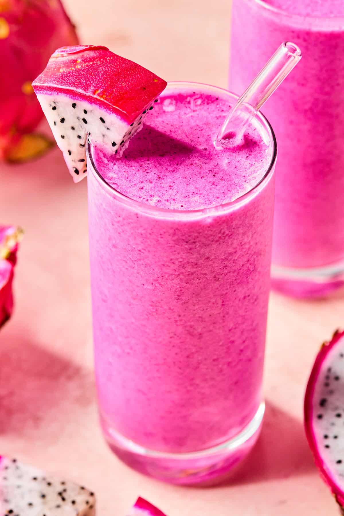 Close-up of a creamy dragonfruit smoothie in a glass with a slice of fresh dragonfruit on the rim.