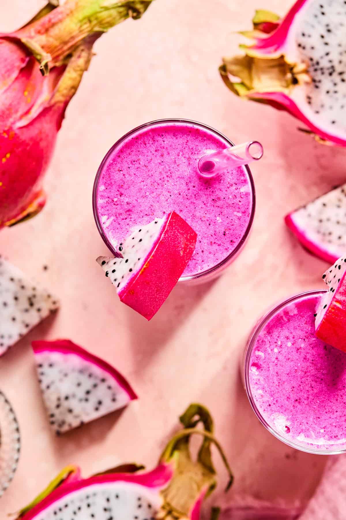 Bird’s eye view of a bright pink dragonfruit smoothie topped with a slice of dragonfruit on the rim of the glass.
