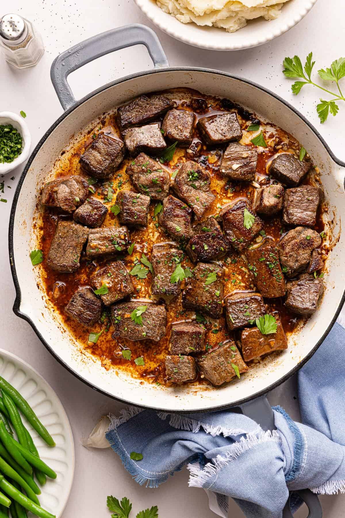 steak bites in a pan with garlic, butter, and parsley