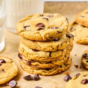 a stack of gluten free chocolate chip cookies on parchment surrounded by cookies