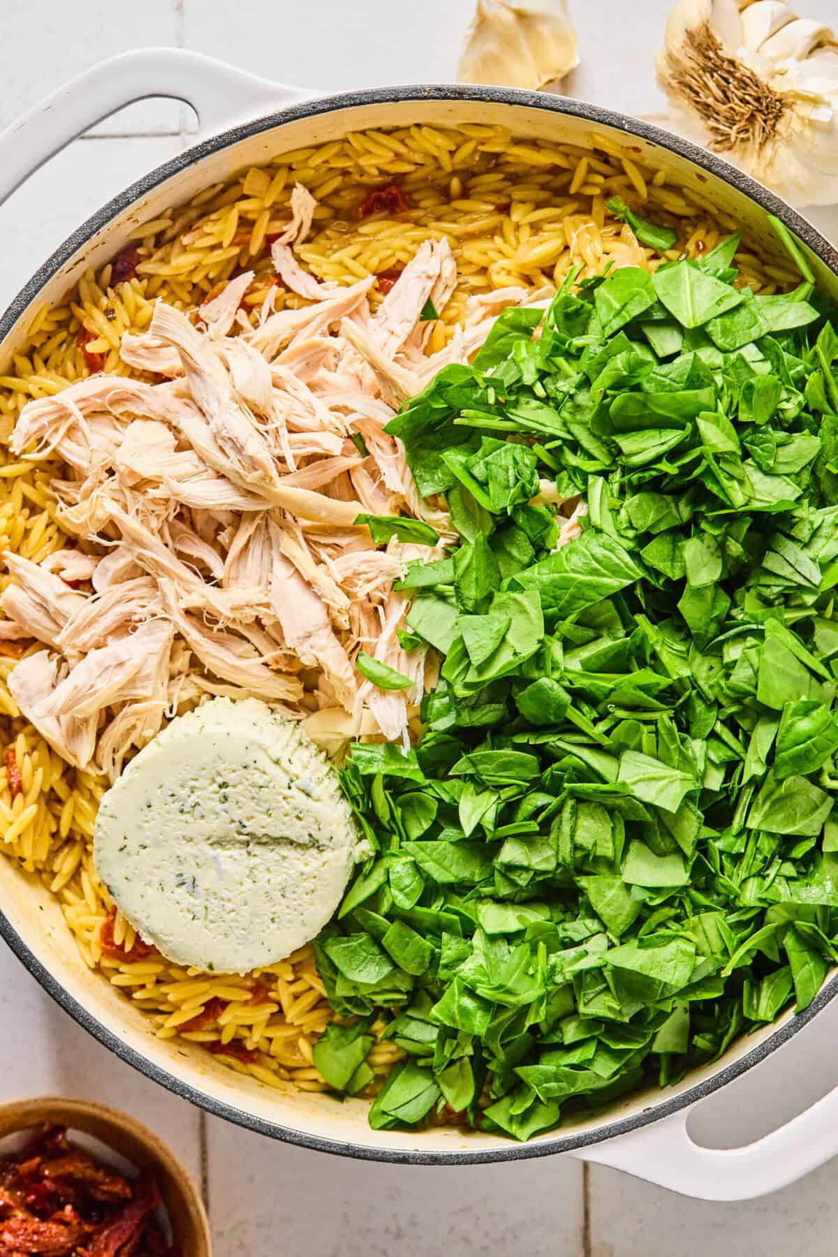 Cooked chicken, spinach, and Boursin cheese in the skillet with the creamy orzo.