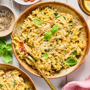 Marry Me Chicken Orzo in a bowl with a fork surrounded by ingredients and a pink napkin