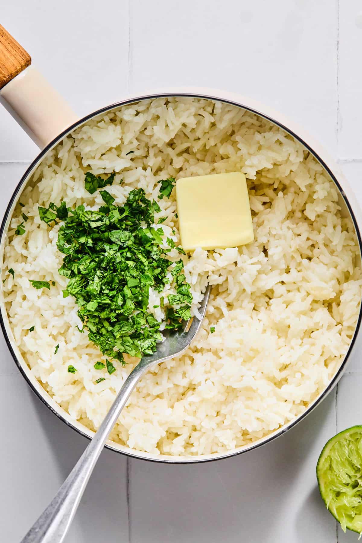 Fluffy cilantro lime rice being mixed with butter, salt, and fresh lime juice in a saucepan.