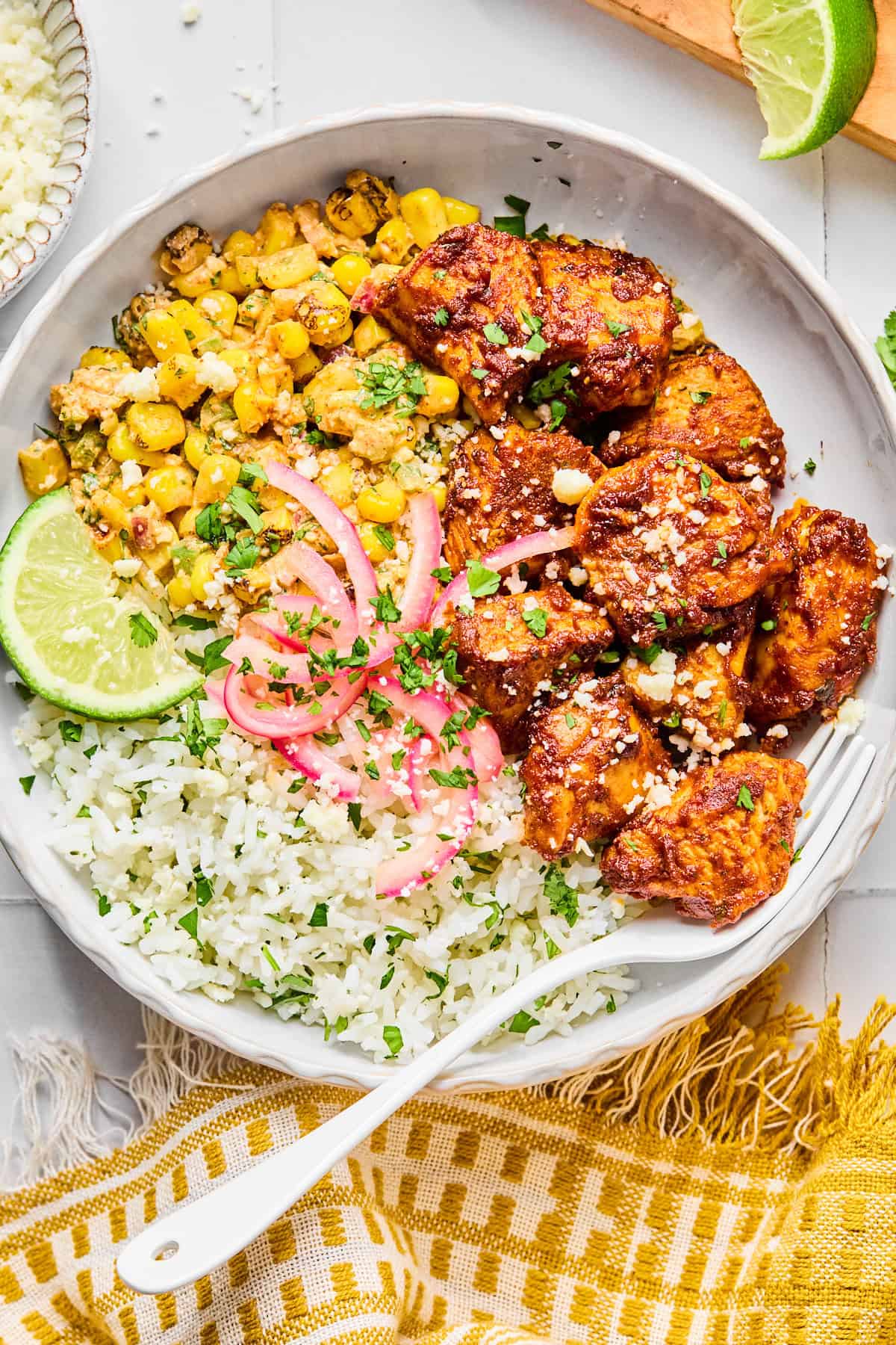 Street corn chicken rice bowls topped with fresh cilantro and served with lime wedges on the side.