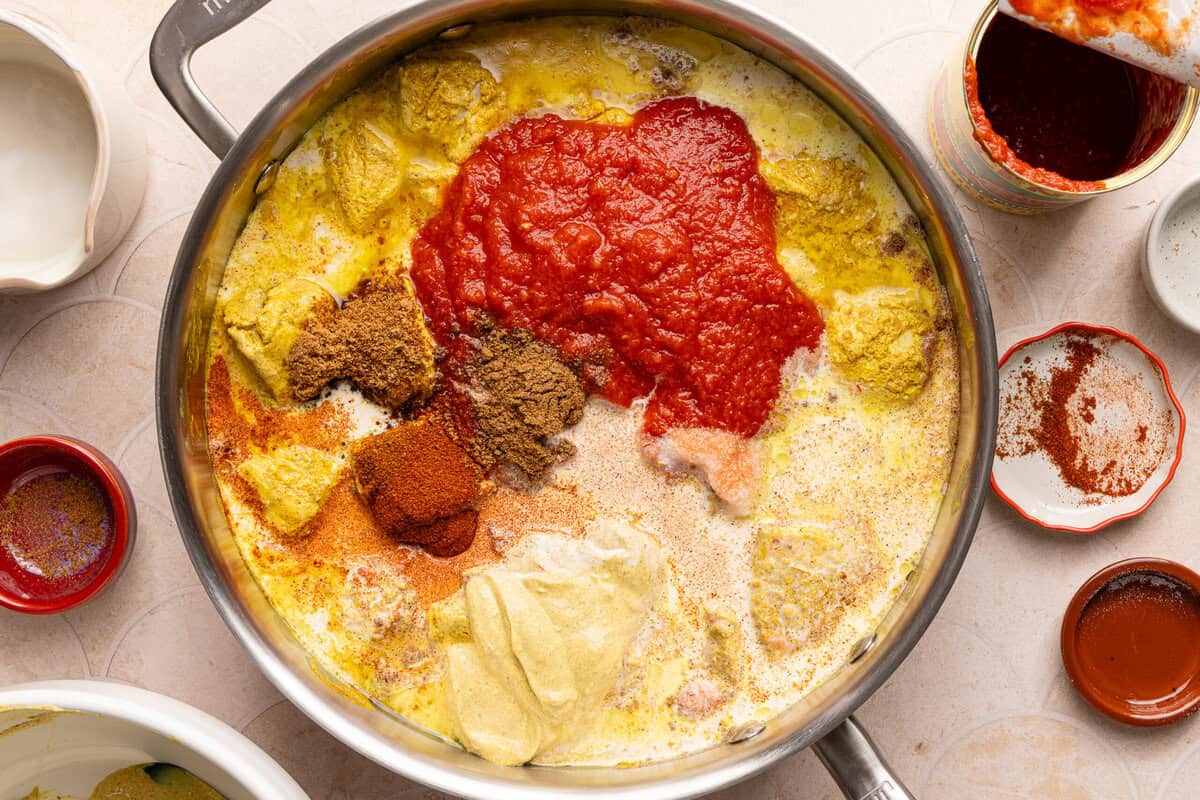 a pan with chicken, tomato sauce, spices, and cream