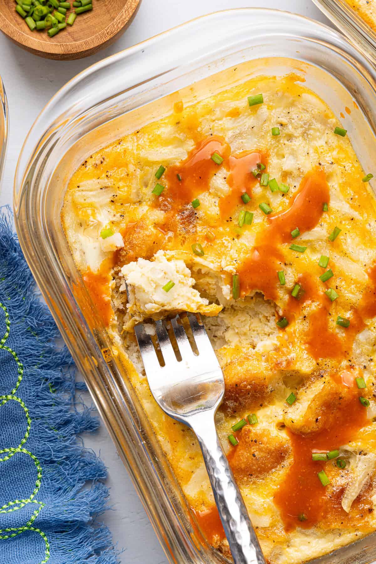 a close-up shot of a chick fil a copycat hash brown scramble bowl topped with hot sauce