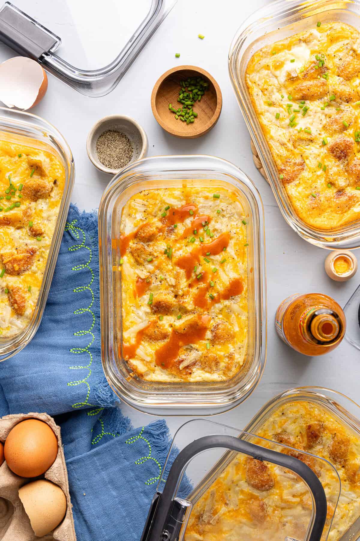 hash brown scramble bowls in glass containers topped with hot sauce
