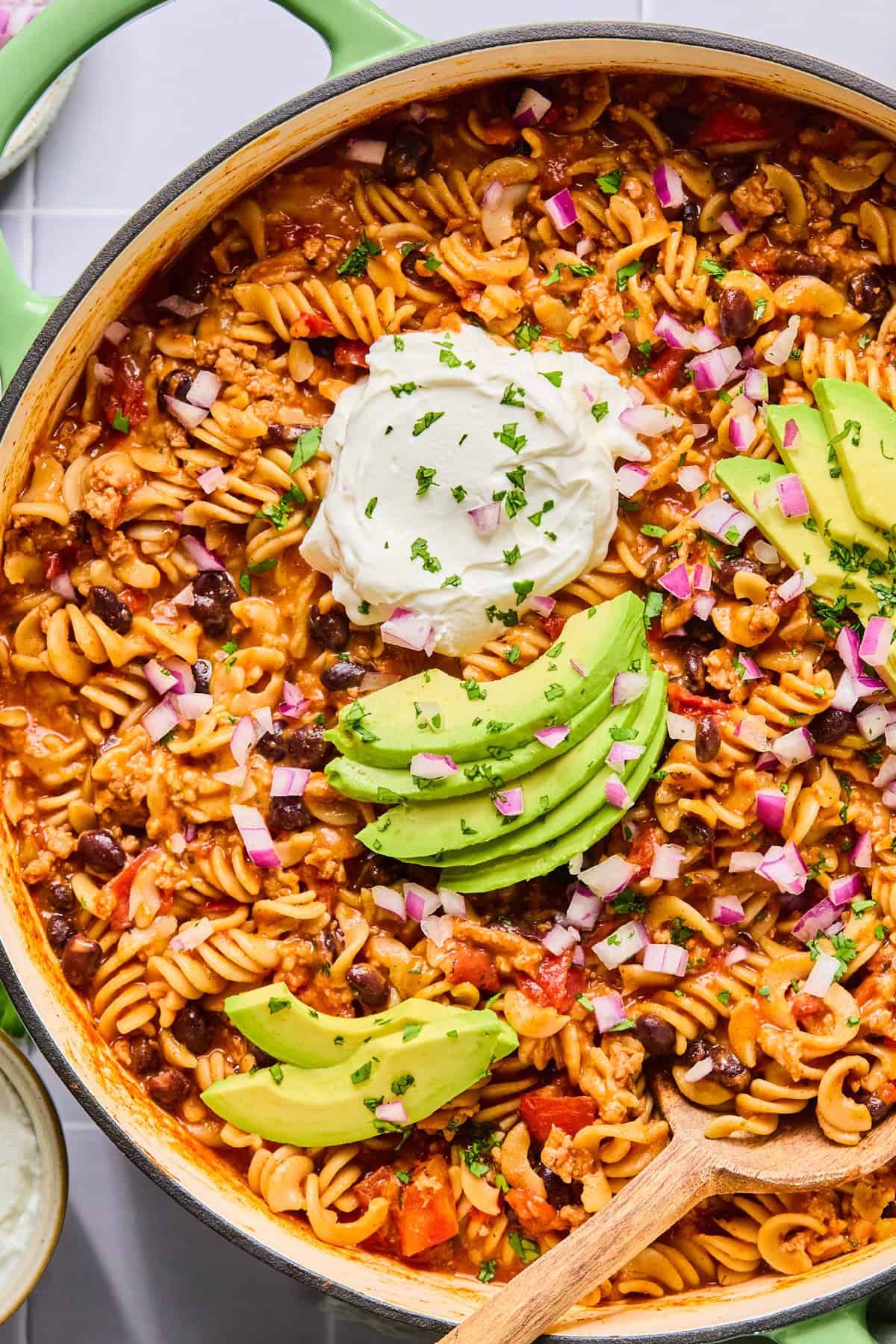 Close-up of one pot taco pasta topped with avocado slices, sour cream, and fresh cilantro.