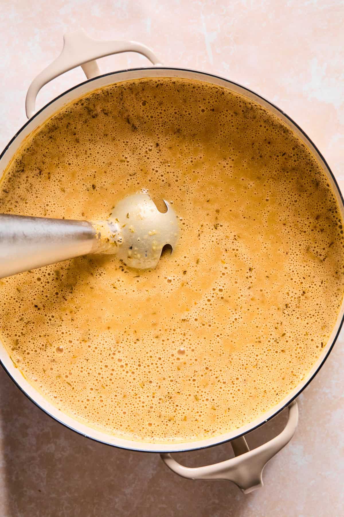 Blending the soup base with an immersion blender.