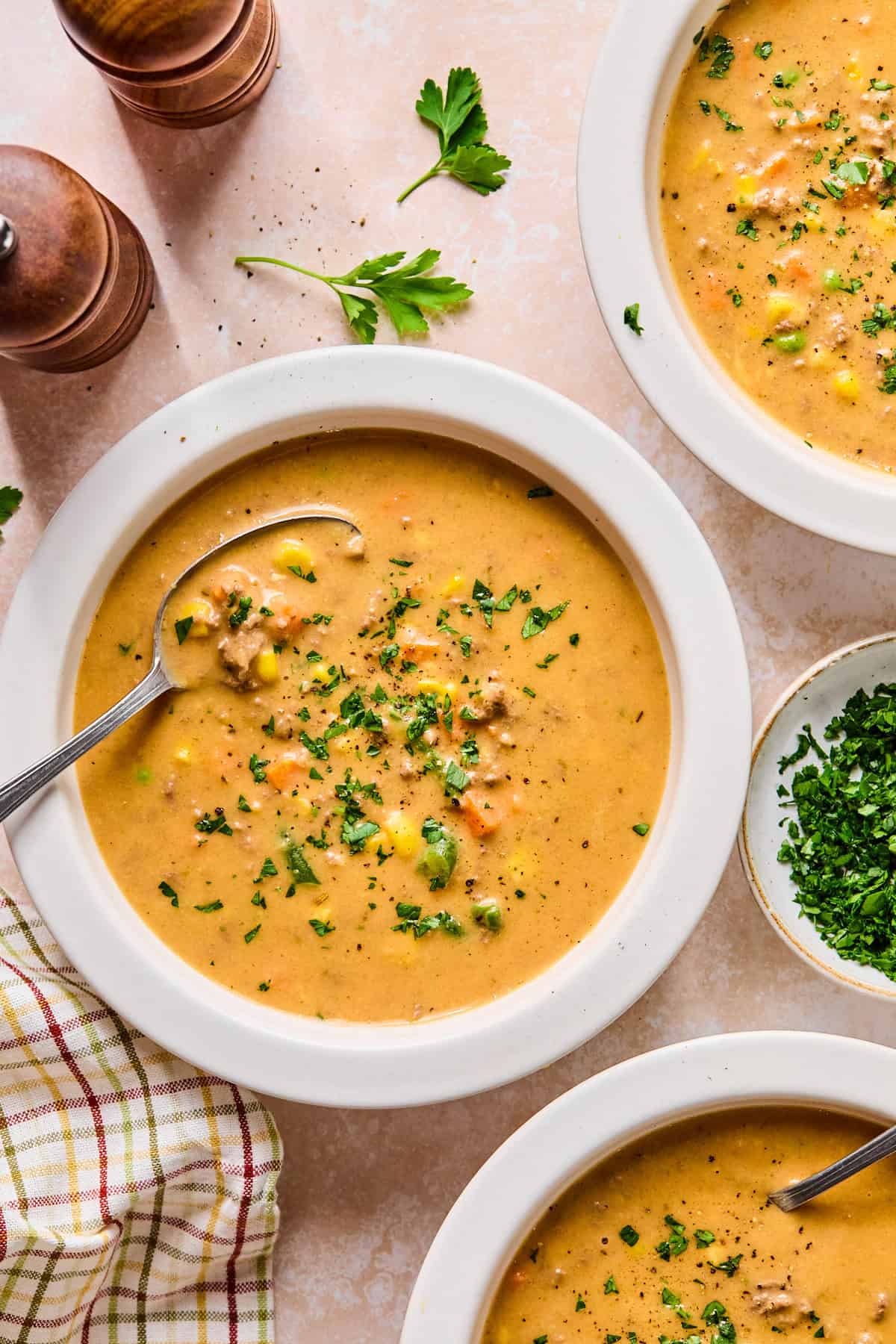 Bowls of shepherd’s pie soup on a light pink countertop with fresh parsley on the side.