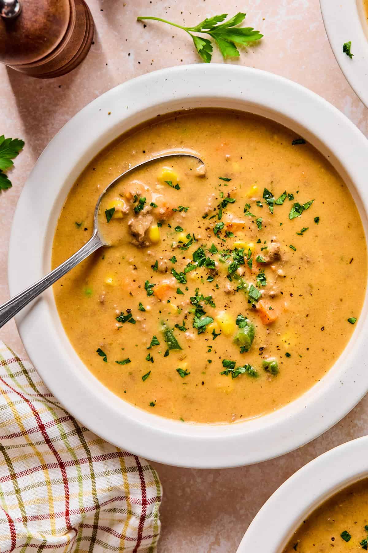 Bowl of creamy shepherd’s pie soup garnished with fresh parsley with a spoon resting inside.