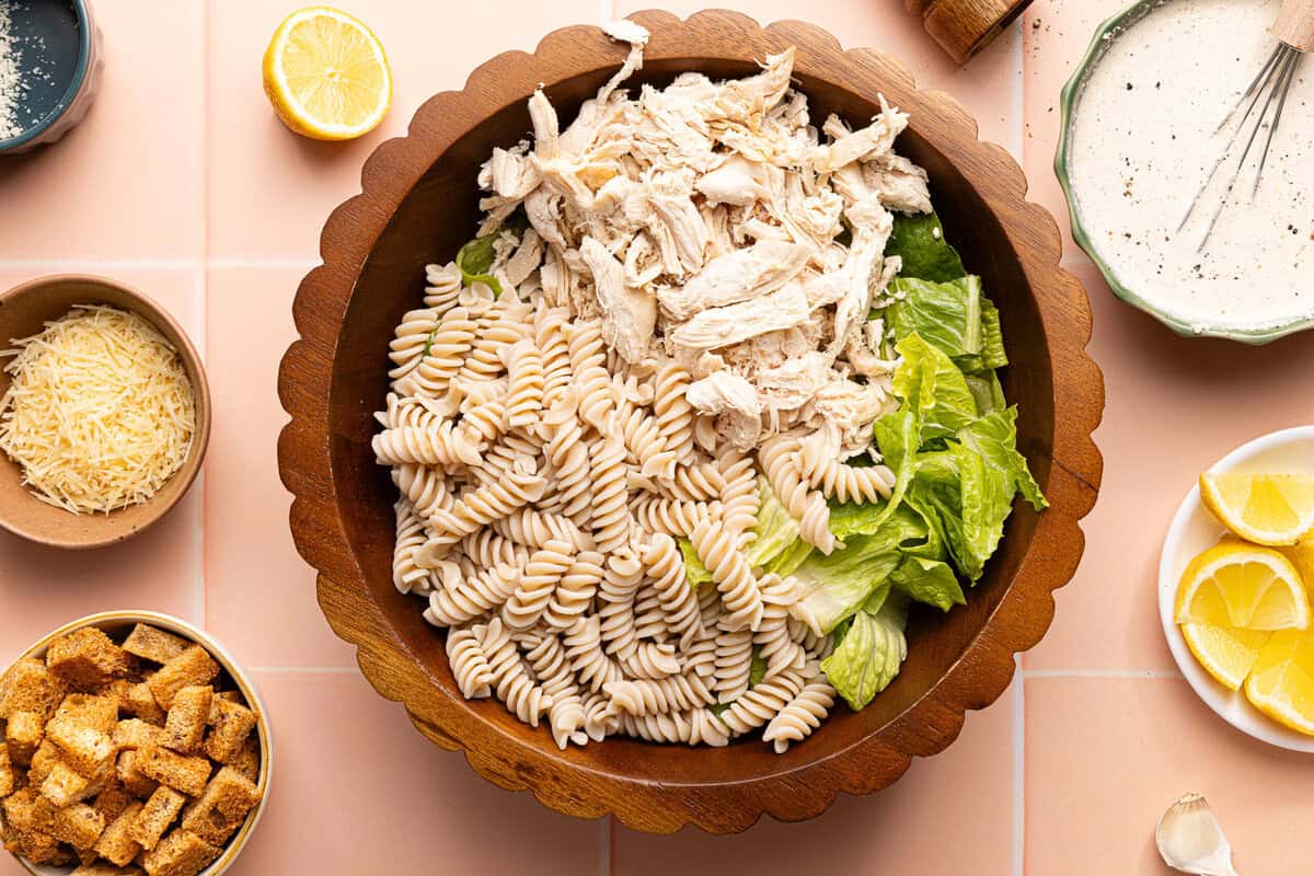 pasta, chicken, and lettuce in a wooden bowl