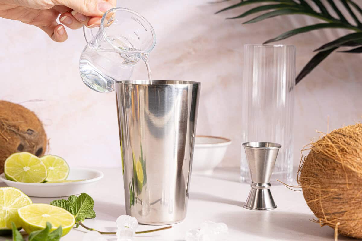 rum being poured into a cocktail shaker