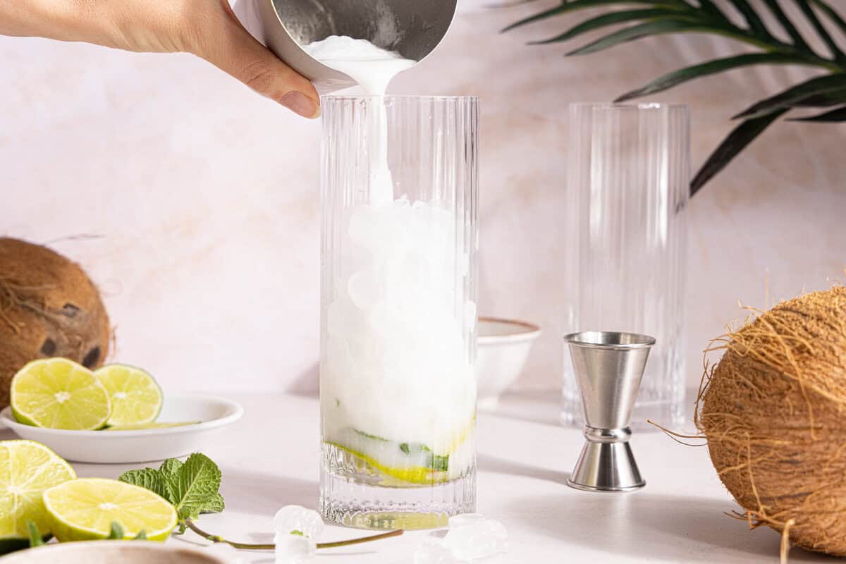cream of coconut and rum being poured over ice in a glass
