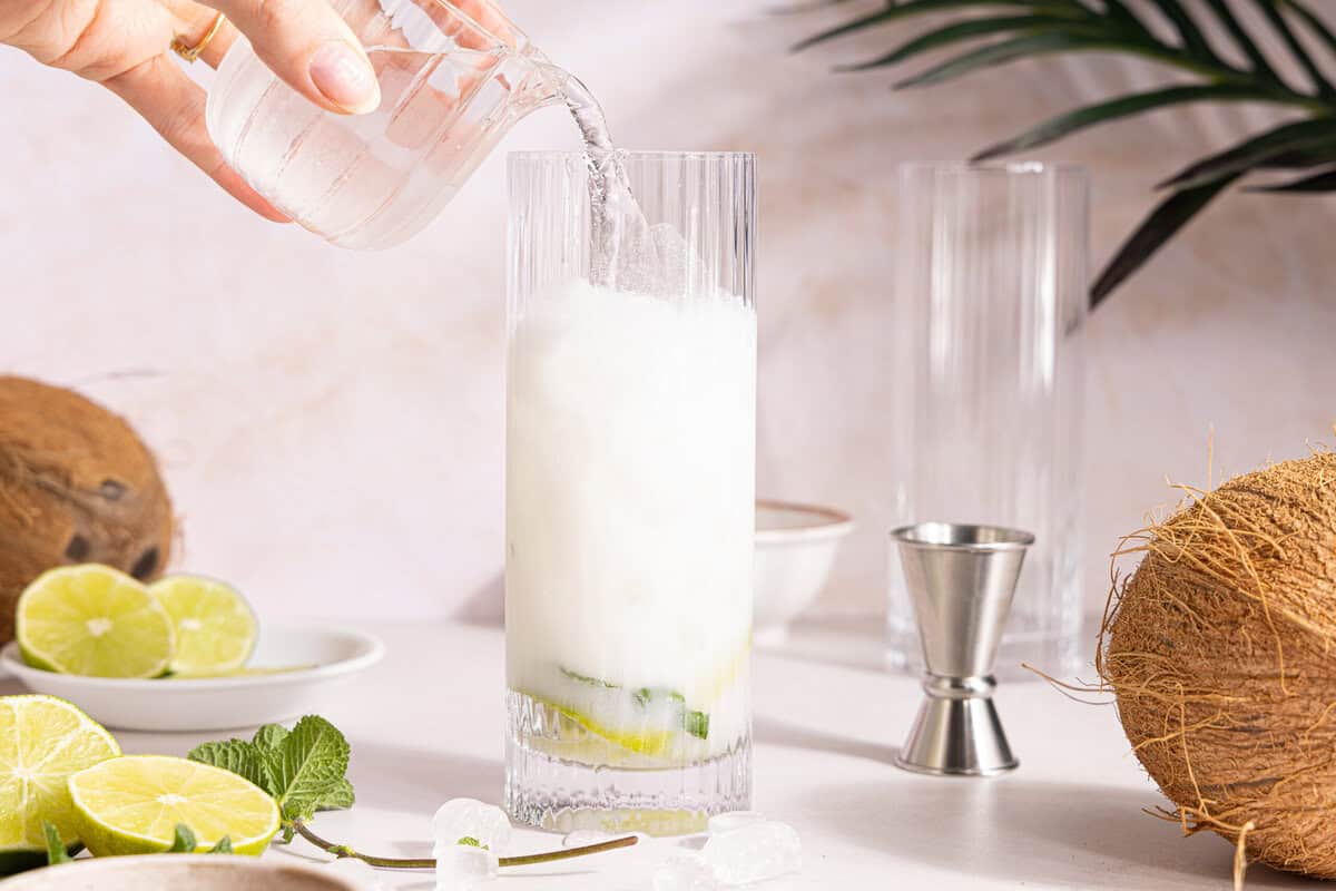 club soda being added to a mojito in a glass