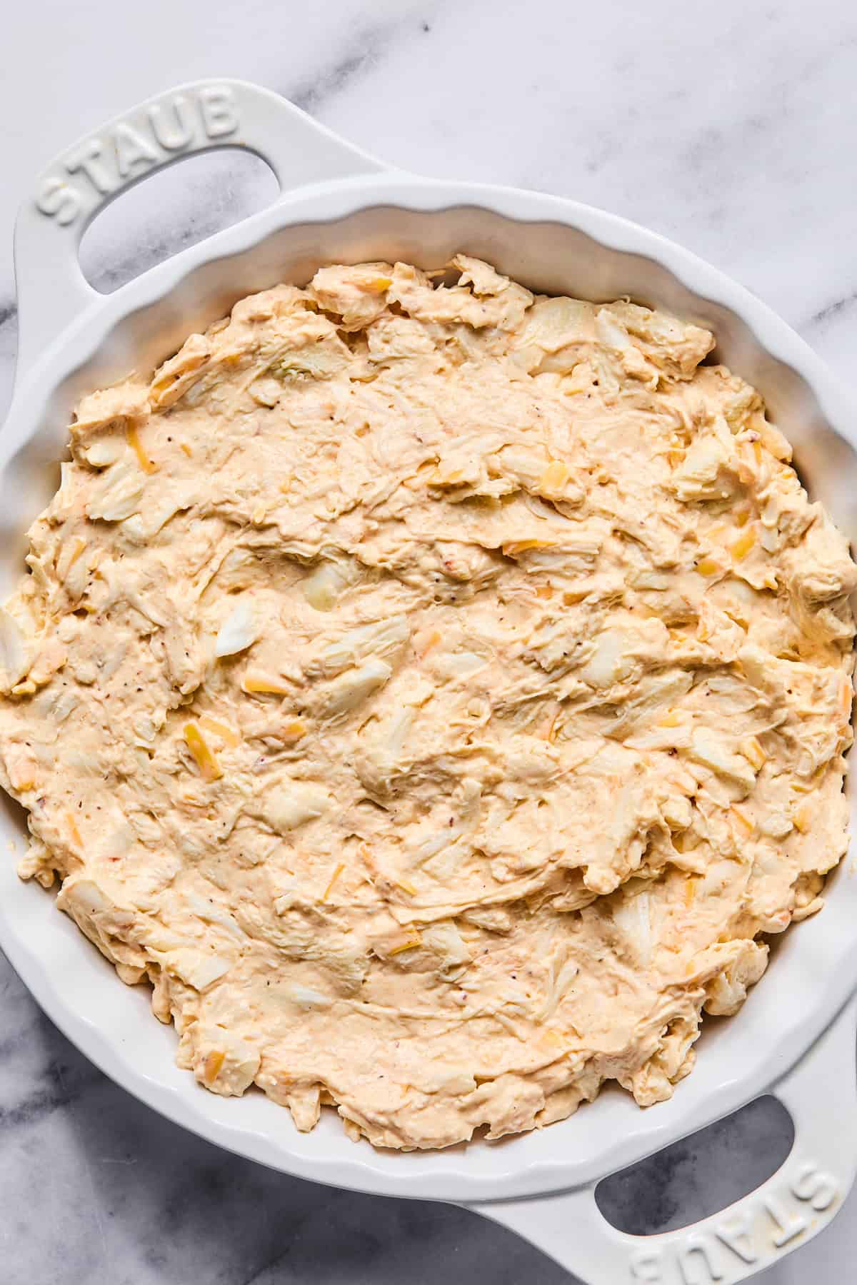 Crab dip mixture spread evenly into a baking dish before baking.