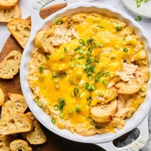 protein Maryland crab dip topped with green onions in a white Staub baking dish surrounded by gluten free baguette slices