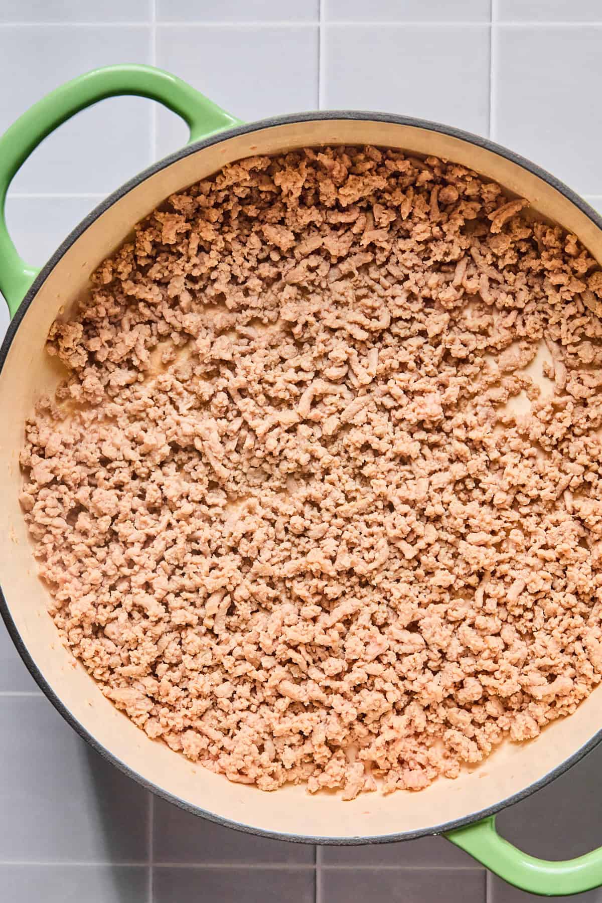 Ground turkey cooking in olive oil in a large skillet, broken up and browned.
