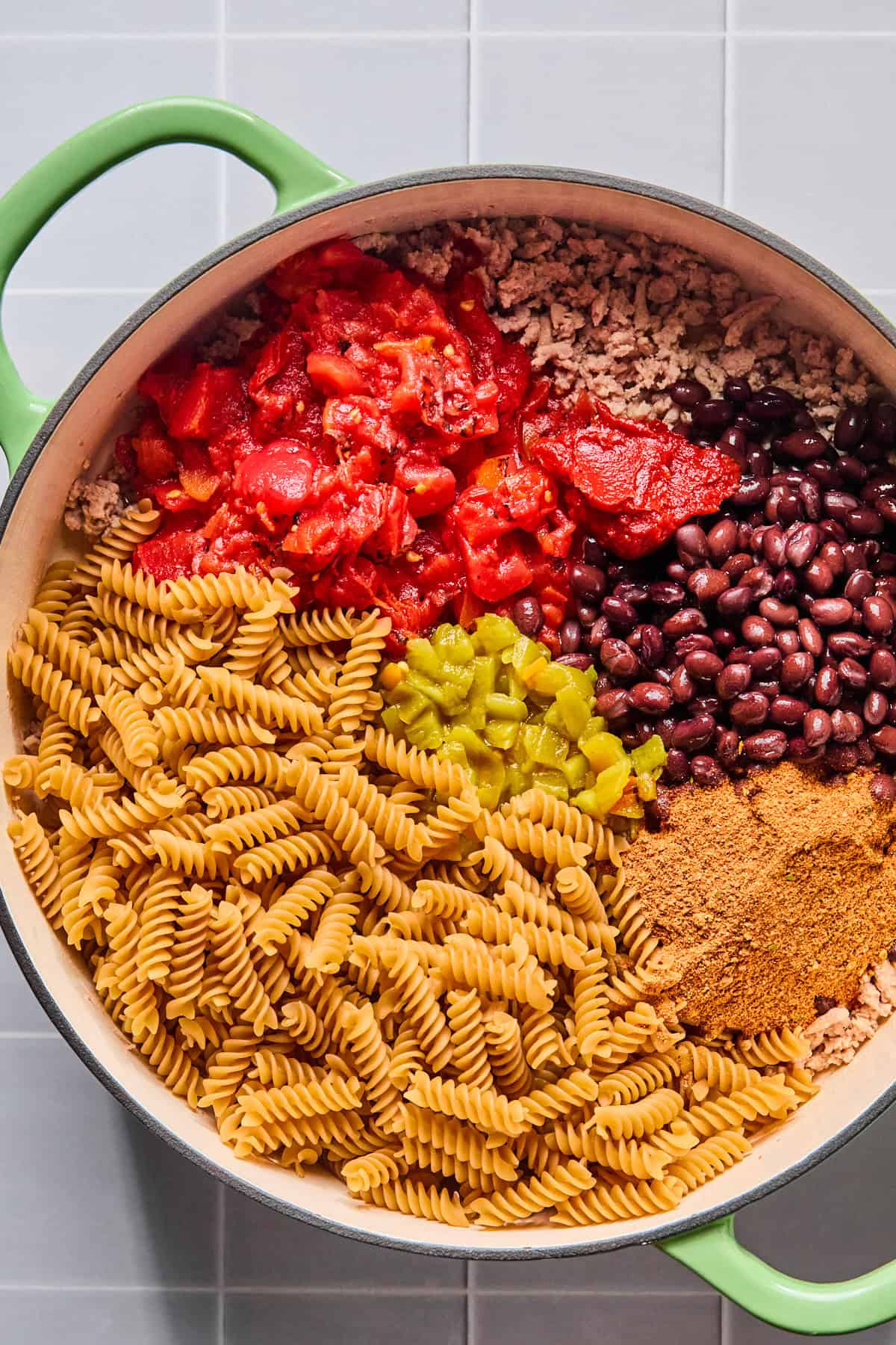 Taco seasoning, tomato paste, diced tomatoes, green chiles, black beans, and pasta in the skillet.