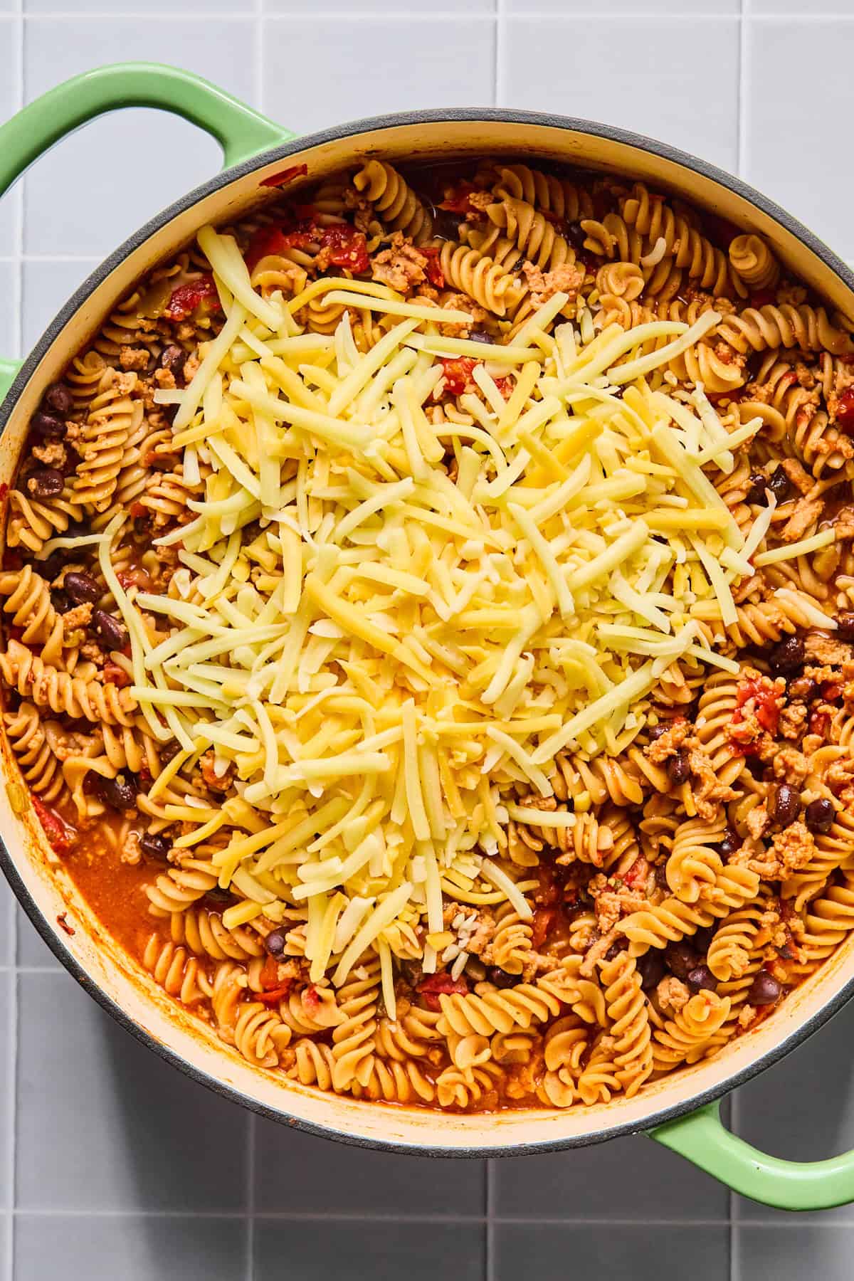 Shredded cheese being stirred into one pot taco pasta until melted and creamy.