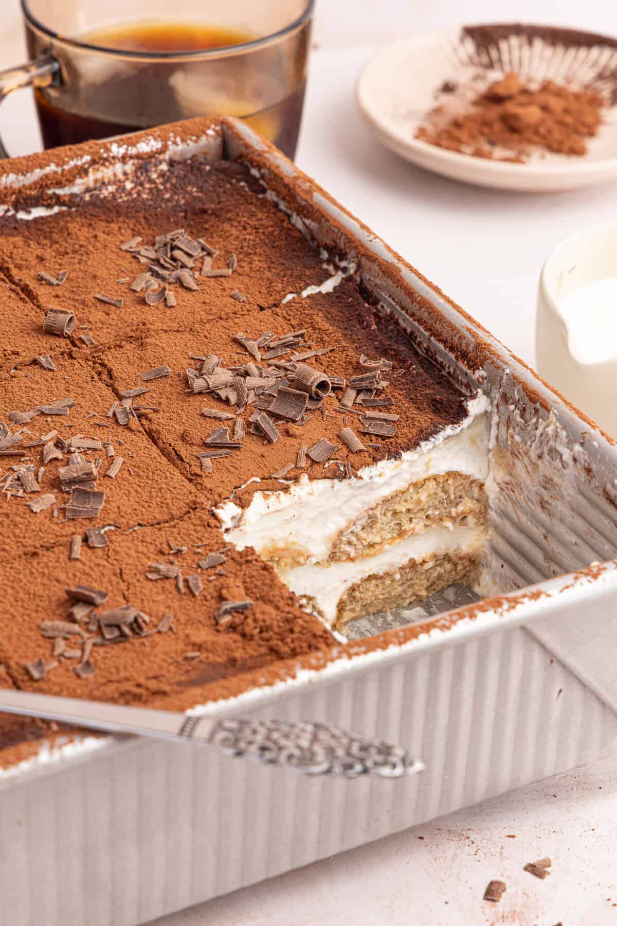 a side view of tiramisu with a slice taken out of the pan
