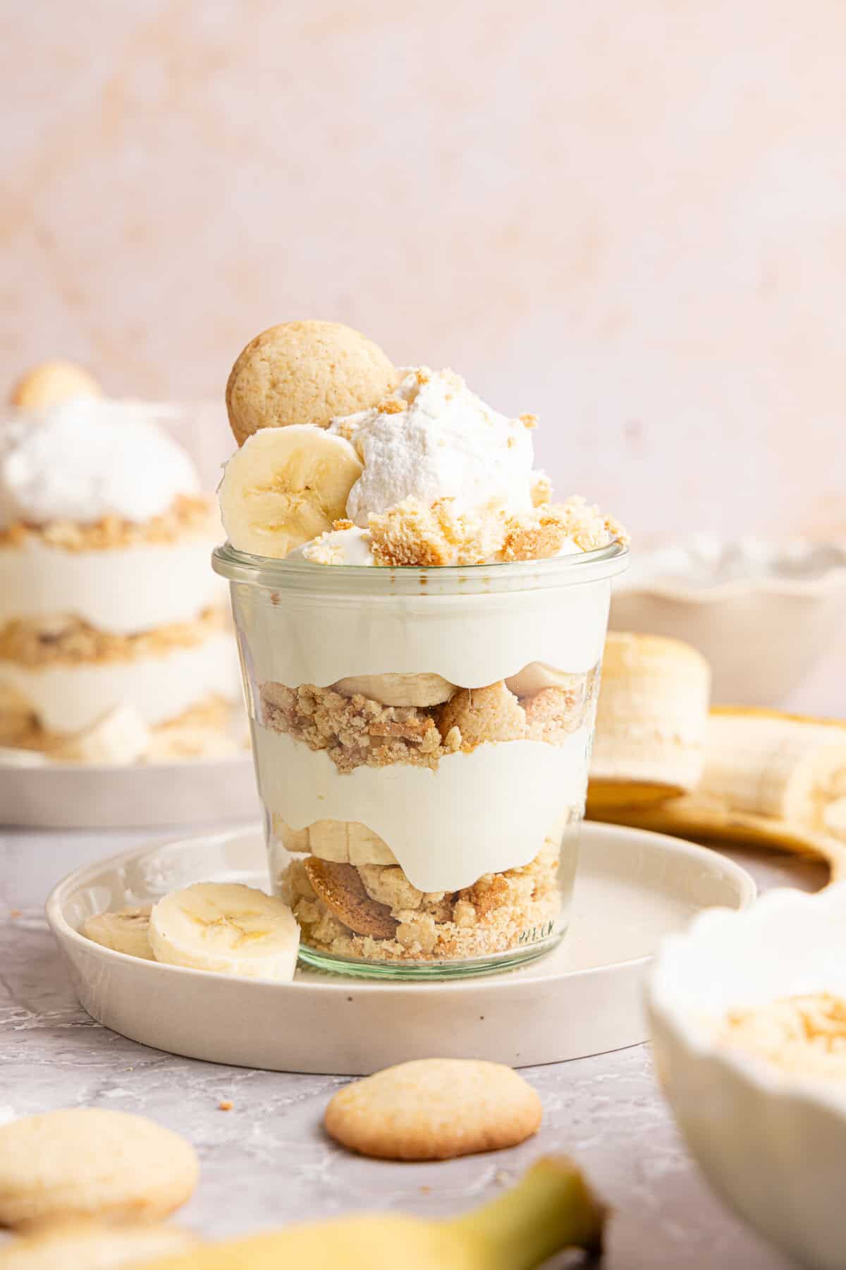 a banana pudding cup with a vanilla wafer and whipped cream on top